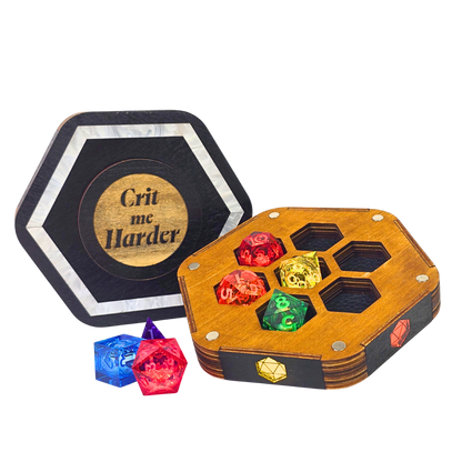 Jeweled Agenda Dice Vault lid engraved Crit me Harder with a pearlized ivory border, beside the open base holding 7 polyhedral dice in honeycomb pockets
