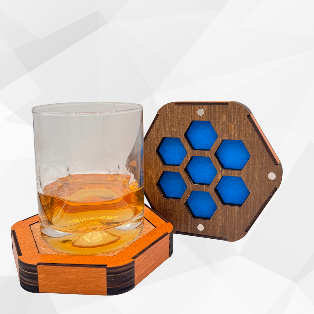 Hexagonal wooden dice box with coaster with blue felt pattern next to a glass of amber liquid on a white background