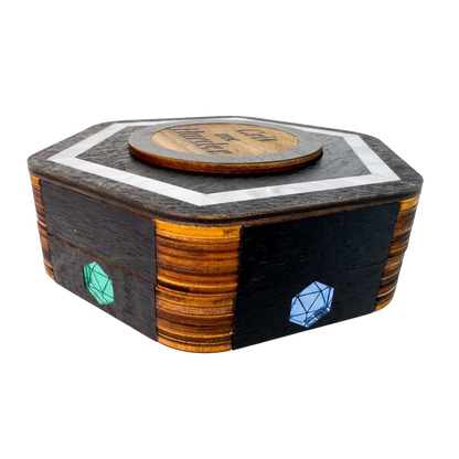 Closed Jeweled Agenda Dice Vault from above with black-stained hexagon lid, pearlized ivory acrylic border, Crit me Harder medallion, and D20 pride gems